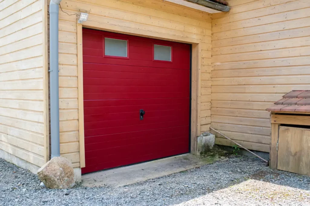 Porte de garage sectionnelle rouge sur bardage bois à lannion
